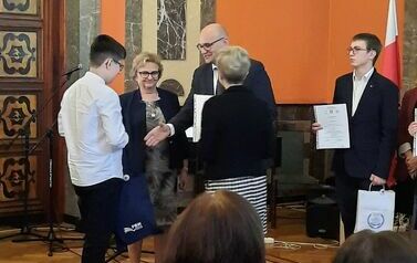 Wojciech Glica odbiera dyplom i nagrodę z rąk organizator&oacute;w Dyktanda
