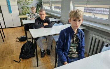 Trzech chłopc&oacute;w siedzących w ławkach podczas konkursu