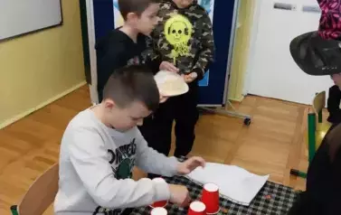Chłopiec przygotowuje wr&oacute;żbę z czerwonych kubk&oacute;w