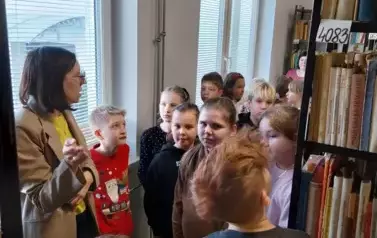 Dzieci słuchają opowiadania bibliotekarki w bibliotece