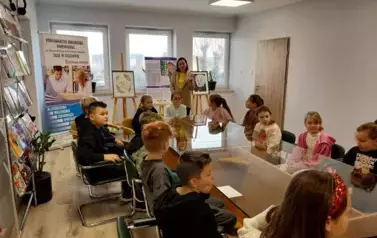 Uczniowie siedzą przy szklanym stole w czytelni