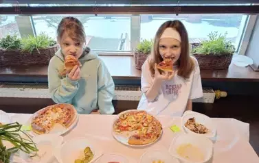 Dziewczynki kosztują wykonaną przez siebie pizzę