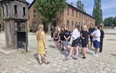 Grupa uczni&oacute;w przy budce obozowego strażnika