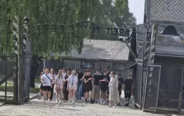 Grupa uczni&oacute;w przed bramą z napisem Arbeit macht frei