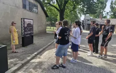 Uczniowie słuchający historii więźni&oacute;w obozu