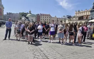 &Oacute;smoklasiści wraz z opiekunami i przewodnikiem słuchający hejnału