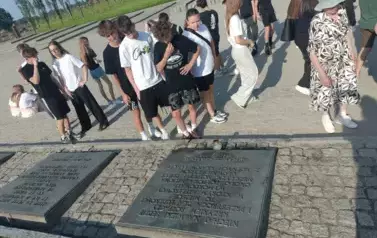 Grupa uczni&oacute;w przed tablicą pamiątkową w Birkenau
