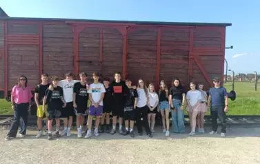 &Oacute;smoklasiści wraz z opiekunami przy wagonie na terenie obozu w Birkenau