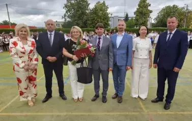 Dyrektor, wicedyrektorzy, zaproszeni goście, nauczycielka odchodząca na emeryturę z bukietem kwiat&oacute;w