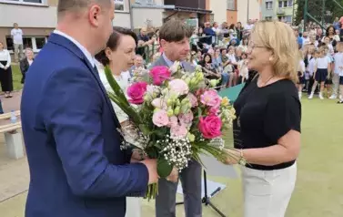 Dyrekcja wręcza kwiaty i podziękowania nauczycielce odchodzącej na emeryturę