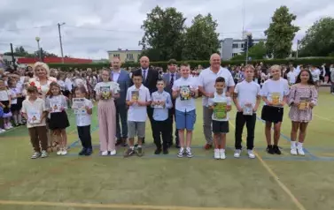 Grupa wyr&oacute;żnionych uczni&oacute;w z zaproszonymi gośćmi stoją na środku