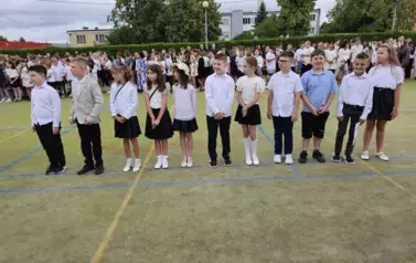 Grupa wyr&oacute;żnionych uczni&oacute;w klasy trzeciej stoją na środku
