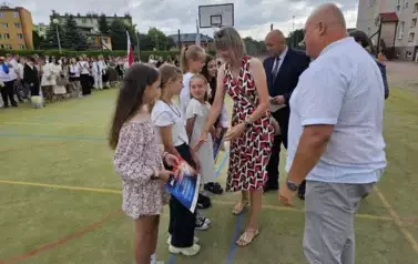 Radni i nauczyciel wręczają nagrody uczniom 