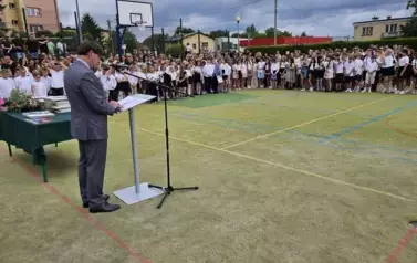 Boisko szkolne, w głębi uczniowie, dyrekcja, nauczyciele, zaproszeni goście, dyrektor przemawia