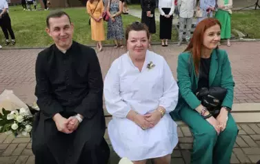 Troje nauczycieli siedzi na ławce, z tyłu stoi grupa pedagog&oacute;w