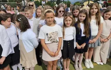 Grupa uczni&oacute;w klas młodszych z wychowawczynią, za nimi rodzice