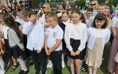 Grupa uczni&oacute;w klas młodszych z wychowawczynią, za nimi rodzice