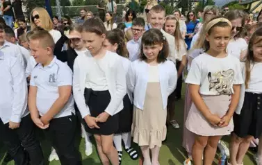 Grupa uczni&oacute;w klas młodszych z wychowawczynią, za nimi rodzice
