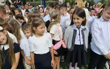Grupa uczni&oacute;w klas młodszych z wychowawczynią, za nimi rodzice