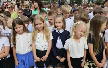 Grupa uczni&oacute;w klas młodszych z wychowawczynią, za nimi rodzice