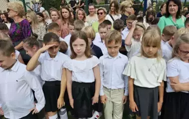Grupa uczni&oacute;w klas młodszych z wychowawczynią, za nimi rodzice