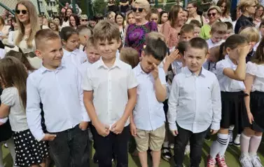 Grupa uczni&oacute;w klas młodszych z wychowawczynią, za nimi rodzice