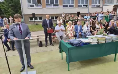 Dyrektor przemawia, za nim siedzą wicedyrektorzy i zaproszeni goście