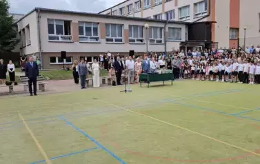 Boisko szkolne, dyrekcja, zaproszeni goście, nauczyciele, uczniowie stoją podczas hymnu państwowego