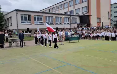 Wprowadzenie pocztu sztandarowego, boisko szkolne, w głębi uczniowie, dyrekcja, nauczyciele