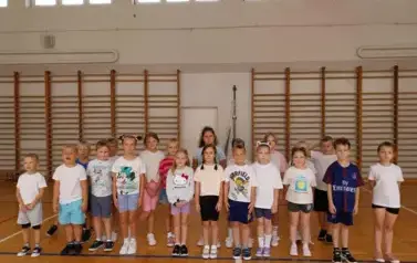 Grupa dzieci ustawiona na zbi&oacute;rce w sali gimnastycznej
