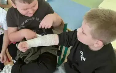 Dw&oacute;ch chłopc&oacute;w bandażuje rękę