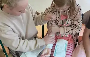 Dwie dziewczynki przyklejają plastry na ręce