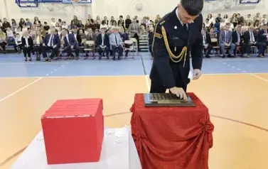 Przedstawiciel Państwowej Straży pożarnej  podczas umieszczania symbolicznej tarczy na tabliczce pamiątkowej