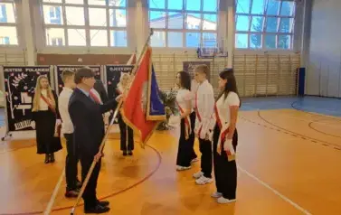 Moment przekazania nowego sztandaru przez dyrektora Kubalskiego uczniom w poczcie