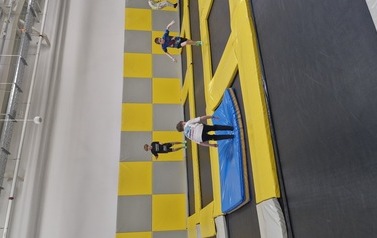 Grupa uczni&oacute;w na trampolinach