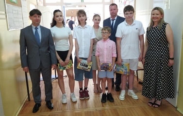 Grupa pięciorga uczni&oacute;w z nagrodami, z lewej dyrektor, z prawej wicedyrektor i nauczycielka
