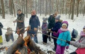 Dzieci ogrzewają się przy ognisku i pieką kiełbaski