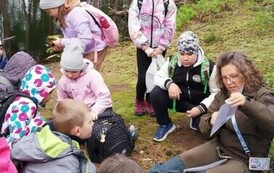 Dzieci siedzą, słuchają opowiadania pani leśnik