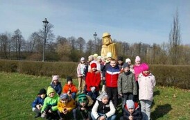 Zdjęcie grupowe &ndash; dzieci na tle rzeźby drewnianej w parku