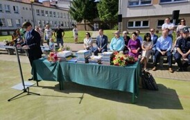 Dyrektor szkoły podczas przem&oacute;wienia i st&oacute;ł z nagrodami