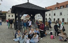Uczestnicy wycieczki  przy studni na kazimierskim rynku