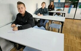 Troje uczni&oacute;w siedzących w ławkach podczas konkursu