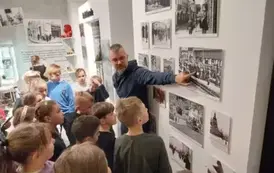 Uczniowie klasy 3 b oglądają zdjęcia z czas&oacute;w wojny i słuchają opowiadania przewodnika