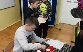 Chłopiec przygotowuje wr&oacute;żbę z czerwonych kubk&oacute;w