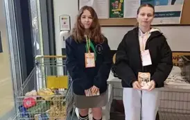 Harcerka z uczennicą trzymają ulotki czekając na darczyńc&oacute;w
