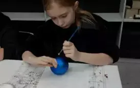 Uczennica maluje bombkę
