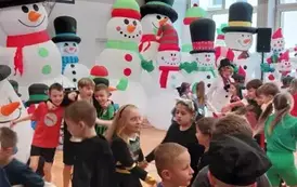 Dzieci podczas zabawy na tle scenografii bałwank&oacute;w