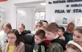 Grupa dzieci przygląda się stanowisku wypożyczania książek