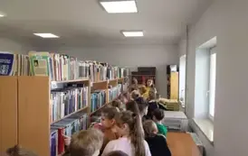 Dzieci podczas oglądania zbior&oacute;w książek na regałach