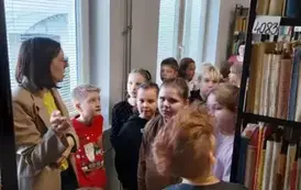 Dzieci słuchają opowiadania bibliotekarki w bibliotece